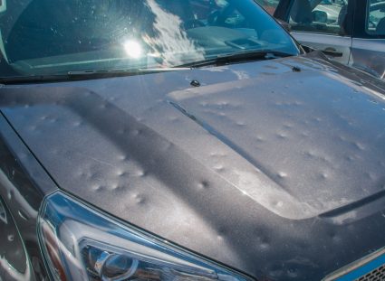 Hood of a car riddled with dents.