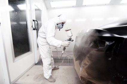 A image of someone painting a car black.