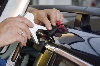 An image of someone using tools for removing dents from vehicles.